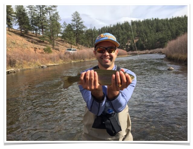 Picture of Pat standing in a stream with a rainbow trout.